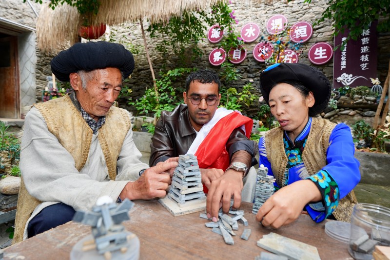 非遗传承人向外国网红讲解羌寨的砌筑工艺。