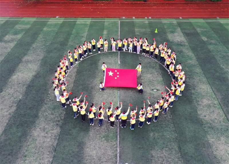 9月28日，四川省广安市广安区思源小学举行“祝福祖国  喜迎国庆”主题教育活动，学生围成圈手舞国旗唱响红歌。学校供图