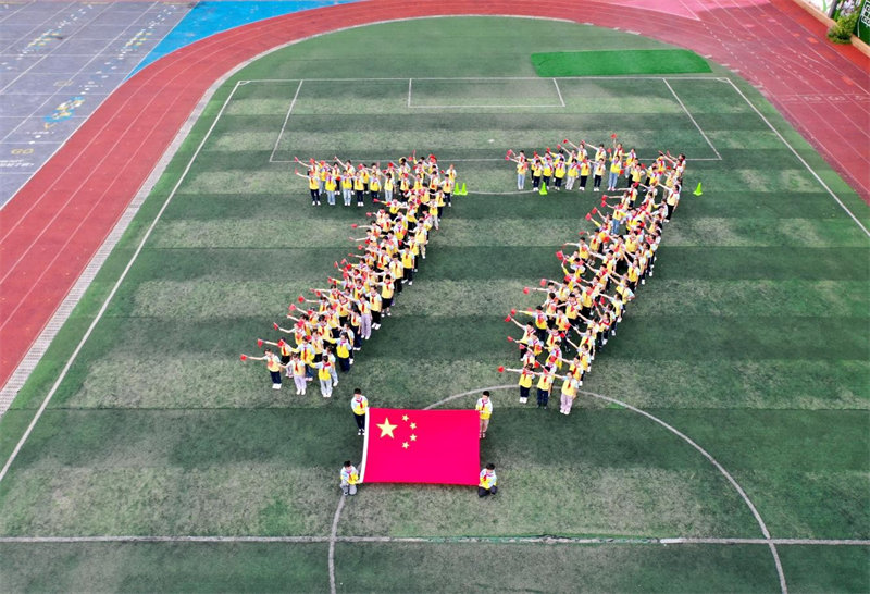 9月28日，四川省广安市广安区思源小学学生在操场上站成“77”队形，手舞国旗唱响红歌，庆祝新中国成立77周年。学校供图