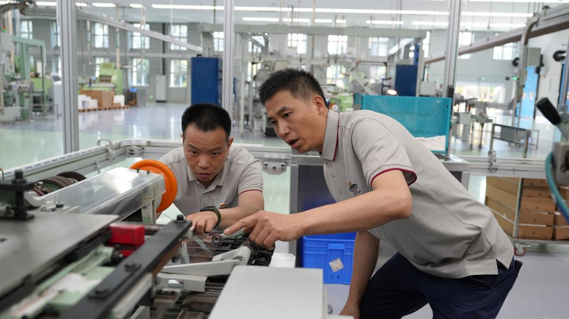 四川中煙西昌卷煙廠首席技師、全國勞動模范劉昌林指導青年員工進行設備調試